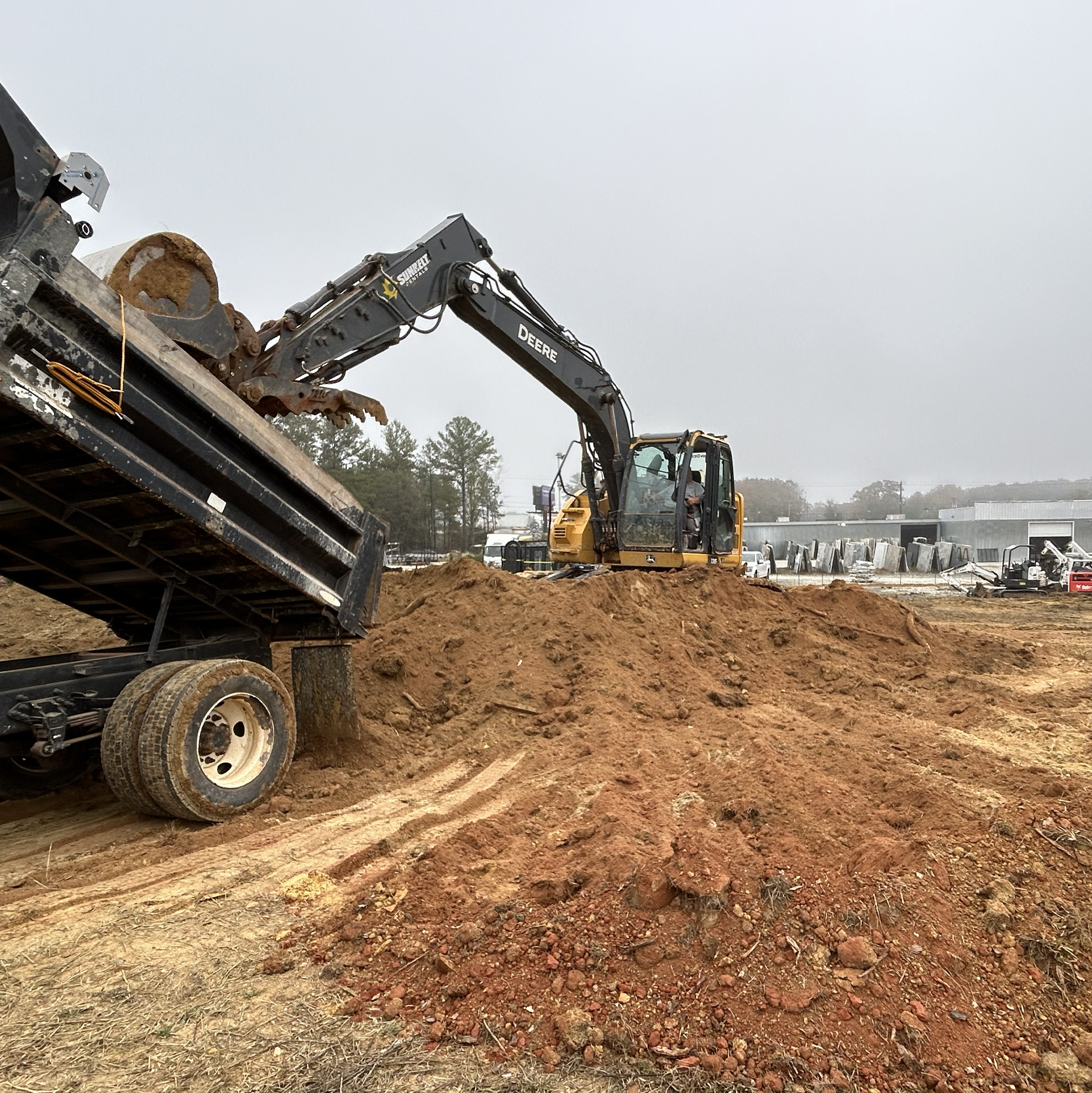 Excavator loading dirt from a dump truck on a construction site.