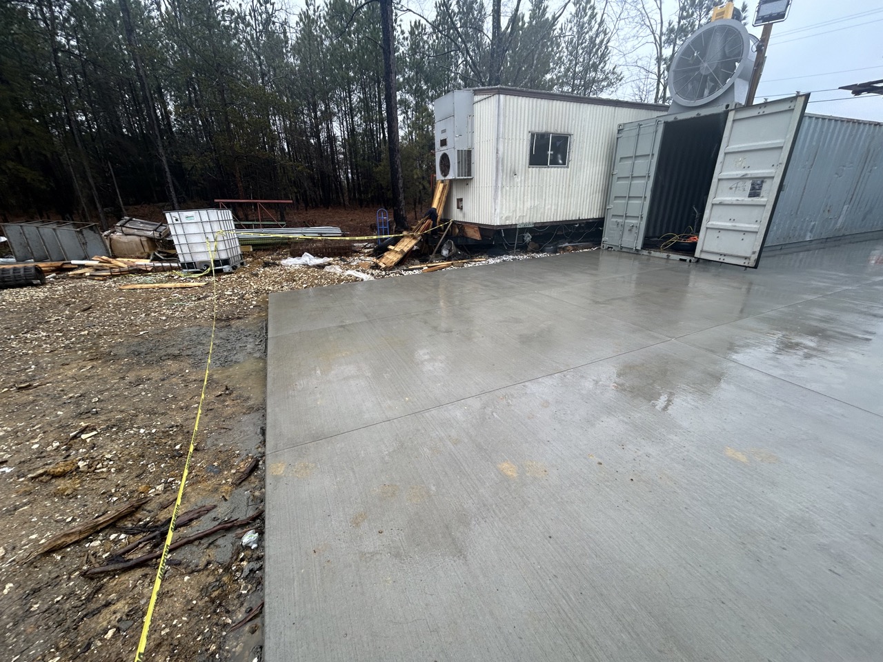 Concrete slab with a construction trailer and a shipping container in a worksite area.